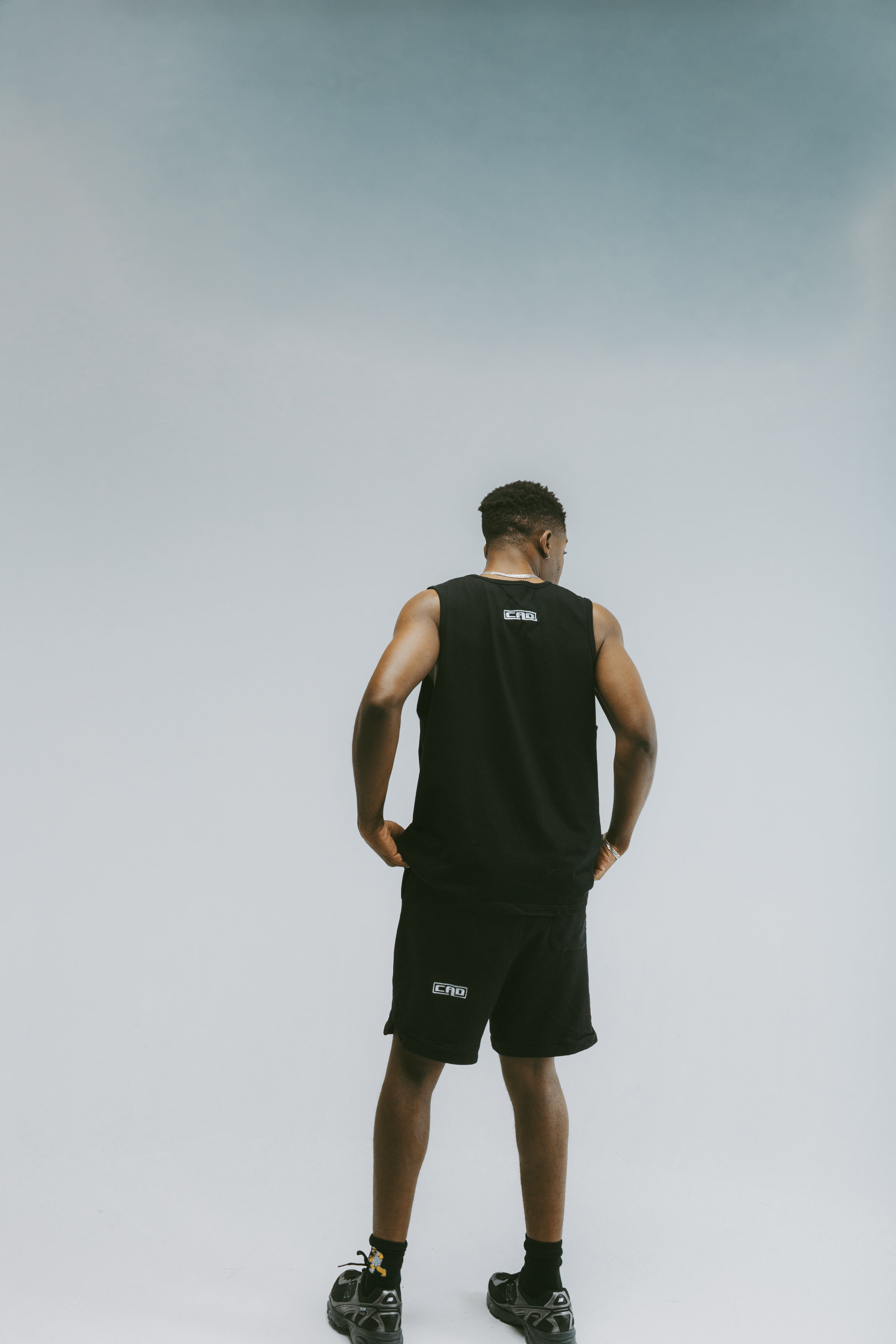 Back view of black Disconnected Shorts worn by model.  Model wearing Disconnected Shorts — black streetwear shorts back angle.