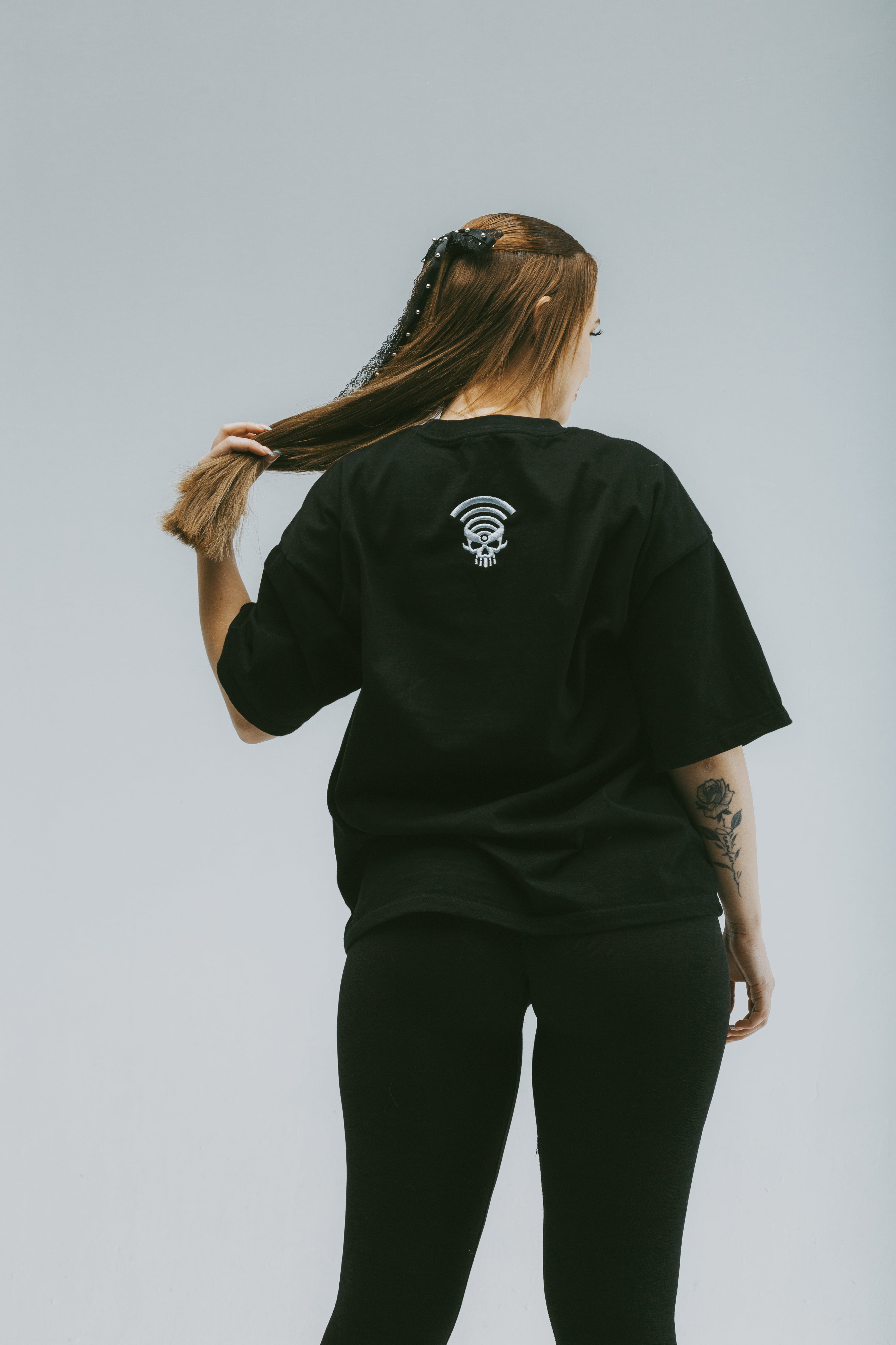 Model wearing a black graphic streetwear tee with drop shoulders and a unique back design.