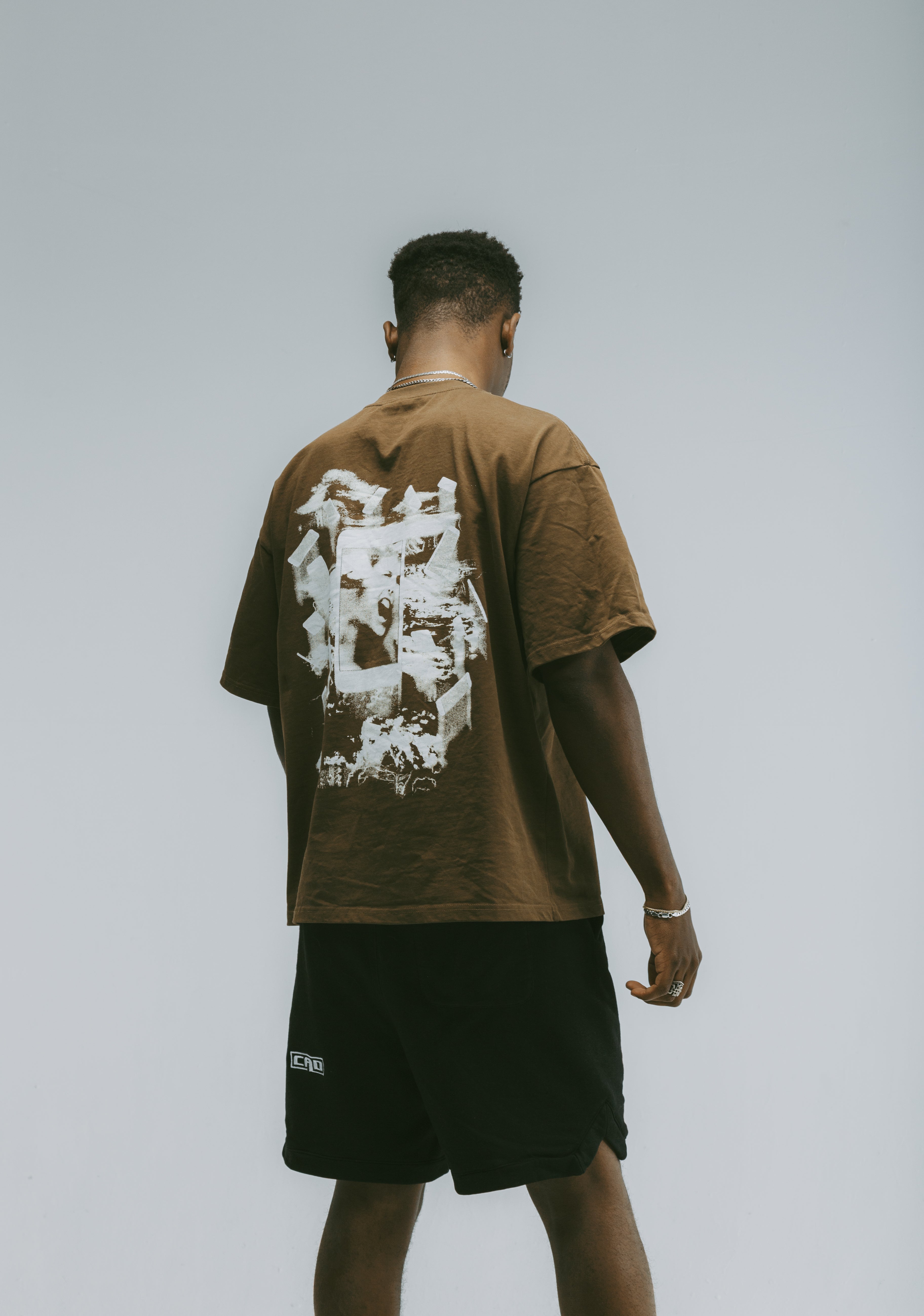 Man wearing the We Are The Content Tee in brown, showcasing the graphic design, part of the Graphic Streetwear Tee collection.